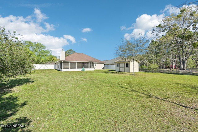 view of yard featuring an outbuilding, a storage shed, a fenced backyard, and a sunroom