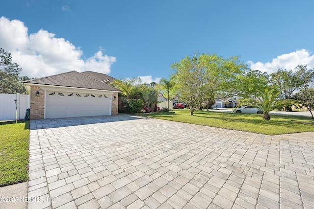 view of front of home featuring decorative driveway, brick siding, a front lawn, and fence