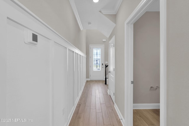 hall with baseboards, light wood-style floors, and ornamental molding