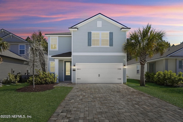 traditional home featuring a garage, decorative driveway, and a front yard