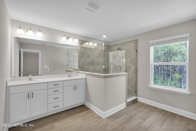 bathroom featuring visible vents, a stall shower, wood finished floors, and a sink