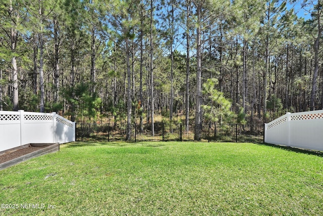 view of yard featuring a view of trees and a fenced backyard