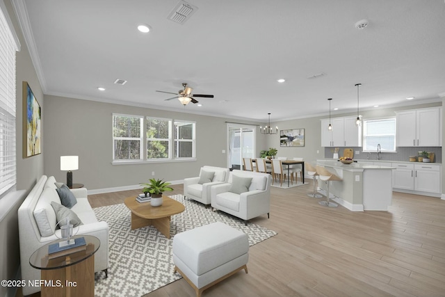 living area featuring visible vents, recessed lighting, light wood-type flooring, and ornamental molding