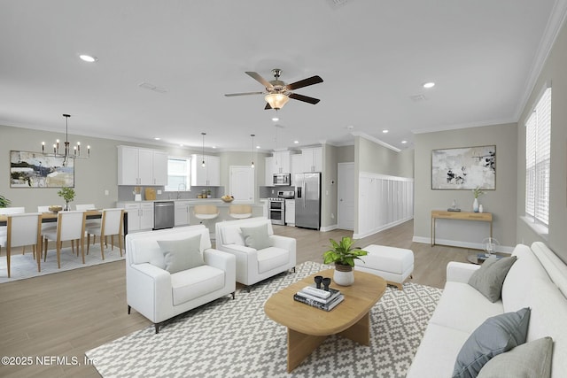 living room featuring crown molding, light wood finished floors, ceiling fan with notable chandelier, and a wealth of natural light