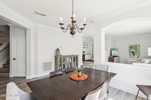 dining room with a notable chandelier, visible vents, and wood finished floors