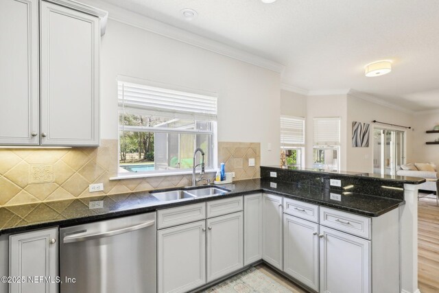 kitchen with open floor plan, dishwasher, ornamental molding, a peninsula, and a sink