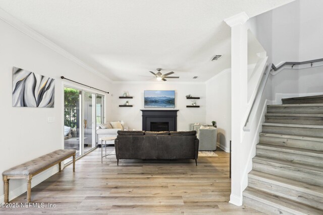 living room featuring light wood-type flooring, visible vents, a ceiling fan, and stairs