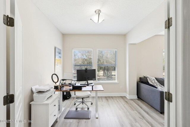 office with baseboards, a textured ceiling, and light wood finished floors