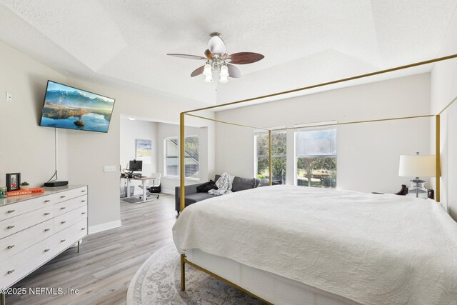 bedroom featuring ceiling fan, light wood-style floors, baseboards, and a textured ceiling