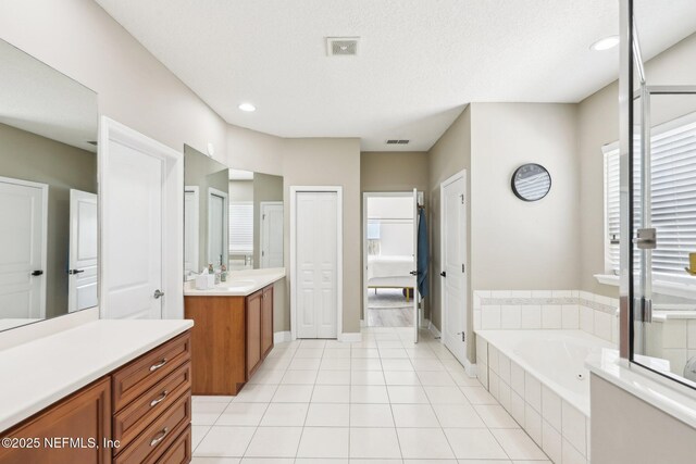 bathroom with tile patterned floors, visible vents, a garden tub, and vanity