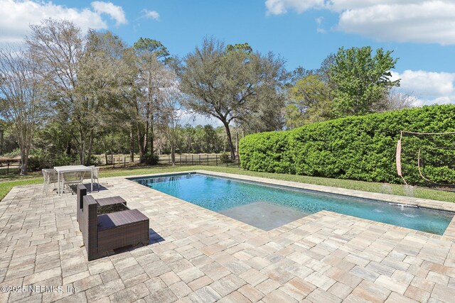 outdoor pool with a patio area, outdoor dining space, and a fenced backyard