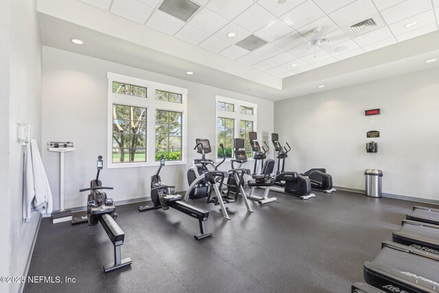 gym featuring baseboards, visible vents, a tray ceiling, recessed lighting, and a drop ceiling