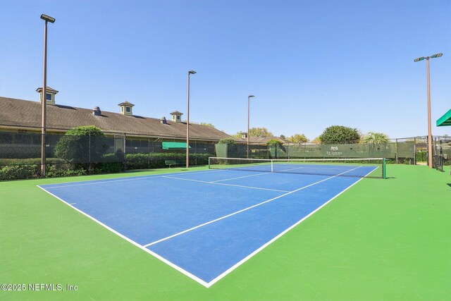 view of tennis court with community basketball court and fence