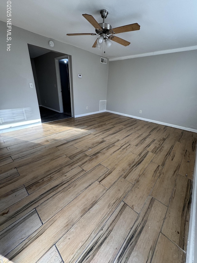 spare room featuring visible vents, a ceiling fan, baseboards, and wood finished floors