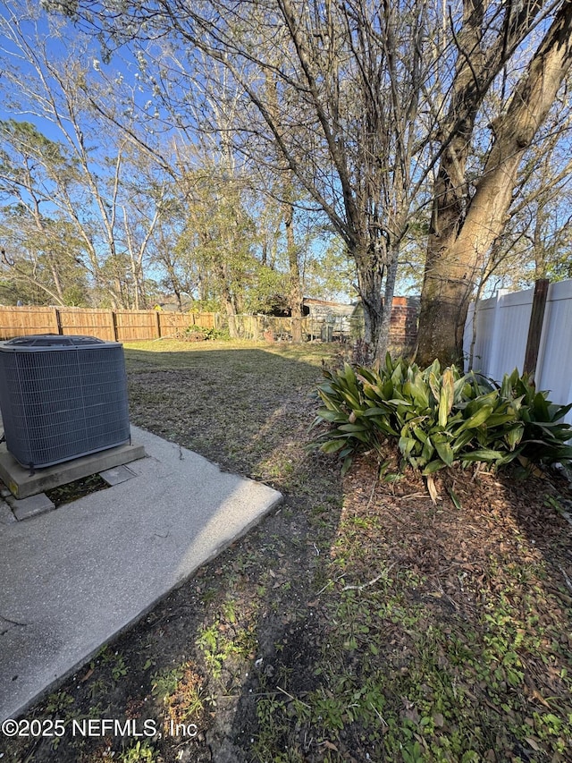 view of yard with a fenced backyard and central AC