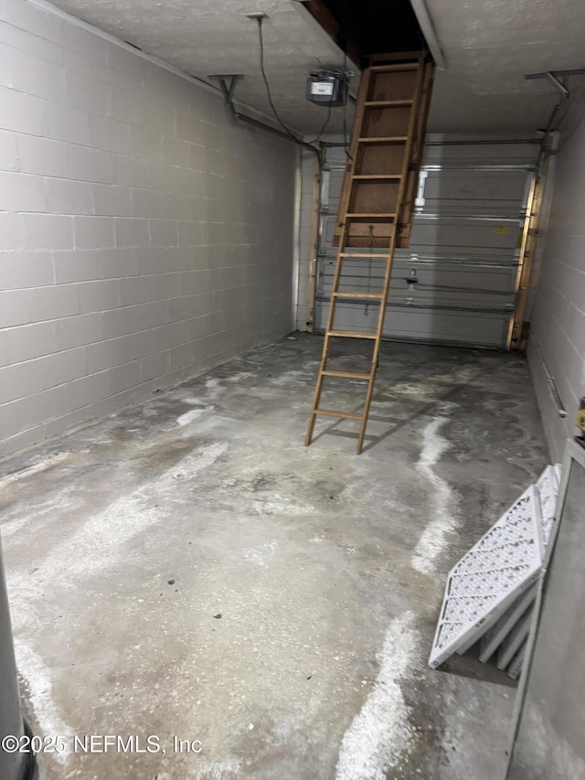 garage with a garage door opener and concrete block wall