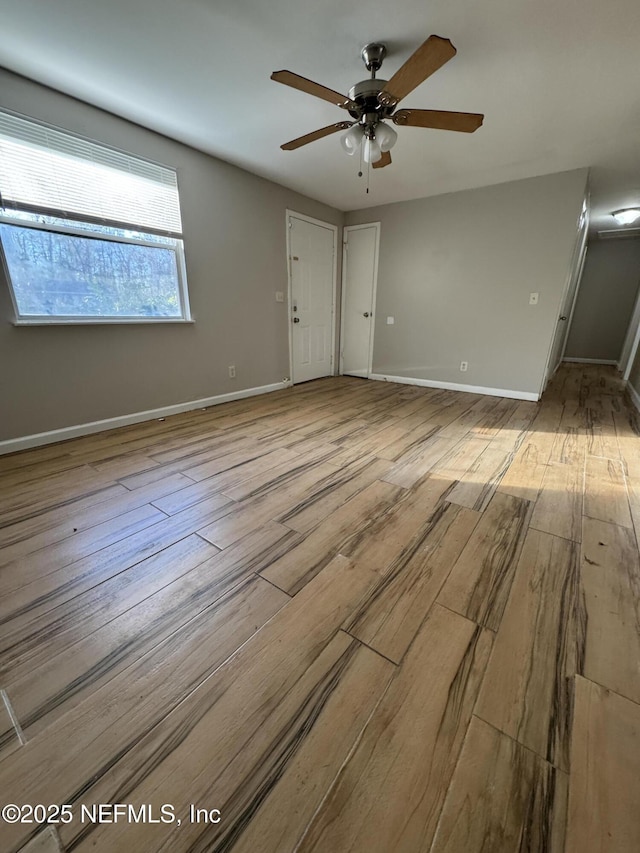 empty room with ceiling fan, baseboards, and wood finished floors