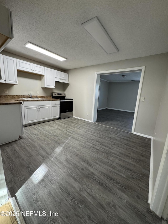 kitchen with dark countertops, dark wood finished floors, white cabinetry, stainless steel range with electric cooktop, and baseboards