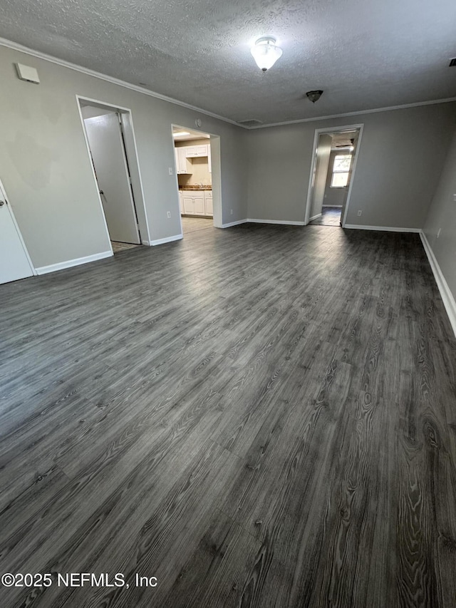 unfurnished living room featuring baseboards, dark wood-type flooring, crown molding, and a textured ceiling