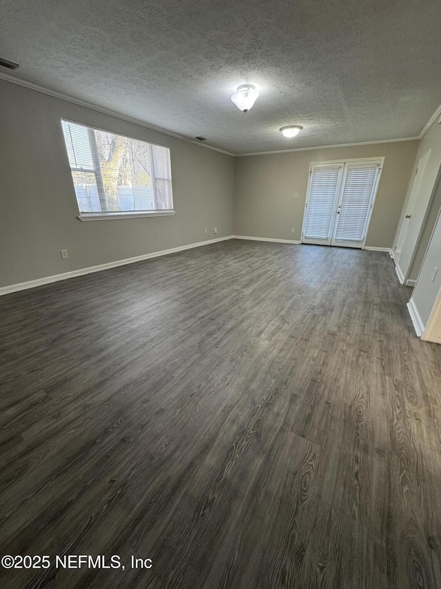 interior space with a textured ceiling, dark wood-type flooring, baseboards, and ornamental molding