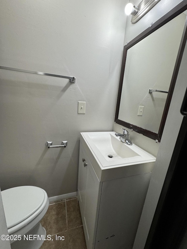 half bathroom featuring vanity, toilet, baseboards, and tile patterned flooring