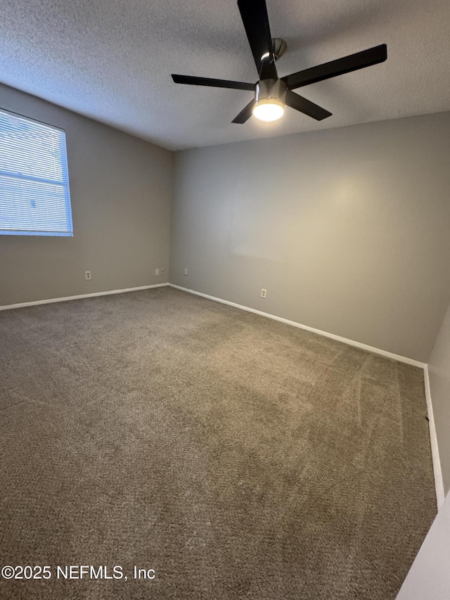 carpeted spare room featuring baseboards, a textured ceiling, and ceiling fan