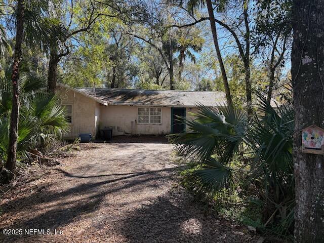 back of house featuring driveway and stucco siding