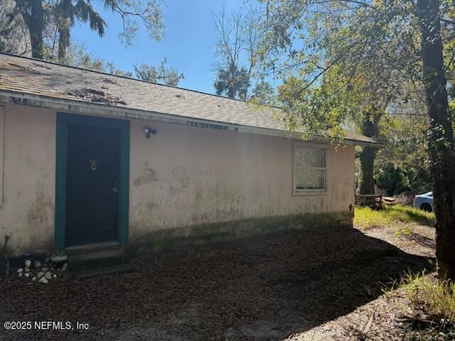 rear view of property featuring a shingled roof