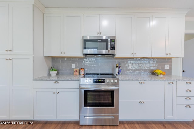 kitchen featuring light stone countertops, appliances with stainless steel finishes, light wood-style flooring, and white cabinetry