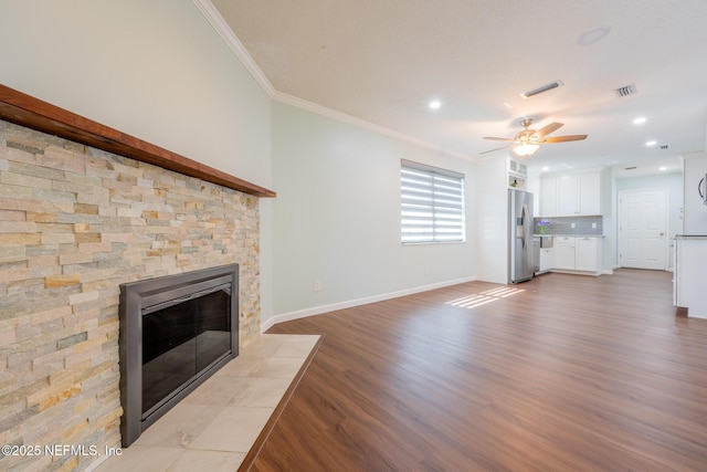 unfurnished living room featuring visible vents, a fireplace with flush hearth, wood finished floors, and ornamental molding