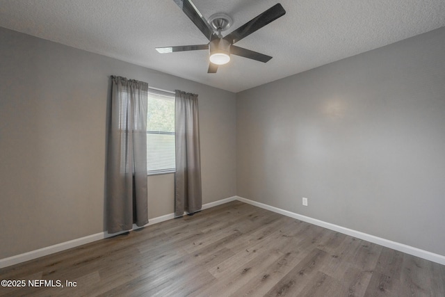 spare room with baseboards, wood finished floors, and a ceiling fan