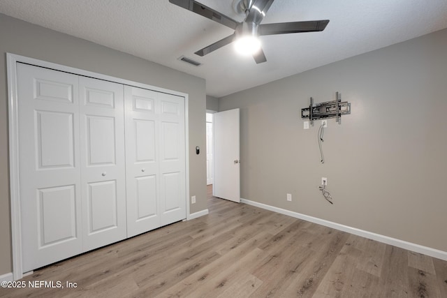 unfurnished bedroom featuring baseboards, visible vents, light wood-style flooring, a closet, and a textured ceiling