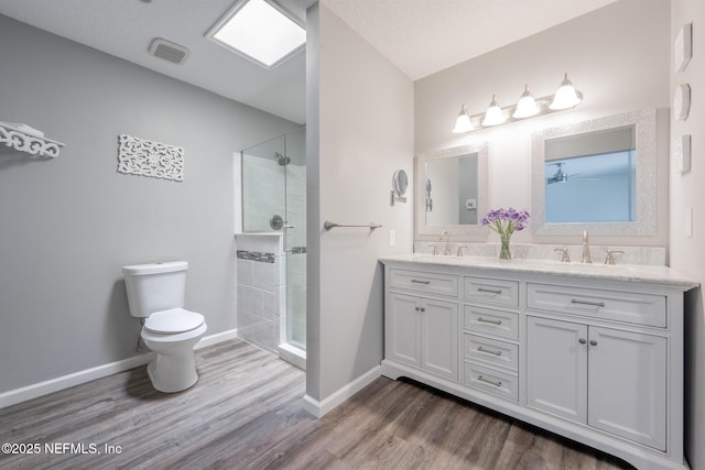 bathroom with a shower stall, toilet, wood finished floors, and a sink