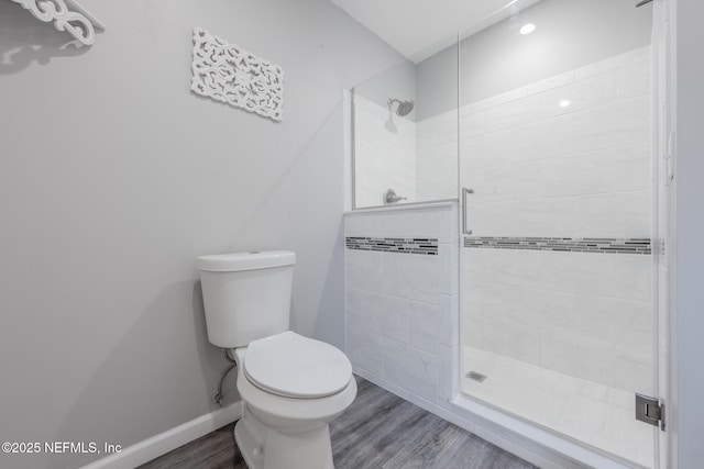 bathroom with a stall shower, toilet, baseboards, and wood finished floors