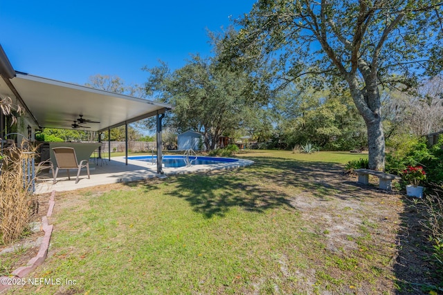 view of yard featuring fence, an outdoor structure, a fenced in pool, ceiling fan, and a patio area