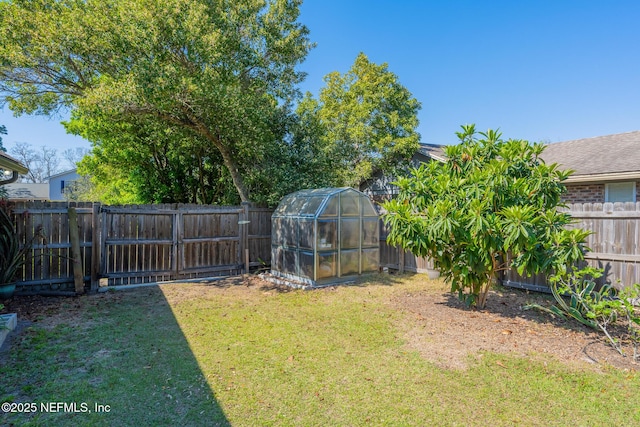 view of yard with an outbuilding, a fenced backyard, and an exterior structure