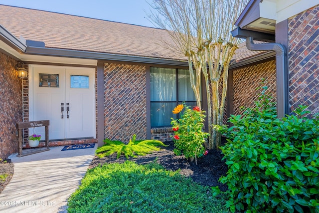 entrance to property featuring brick siding and roof with shingles