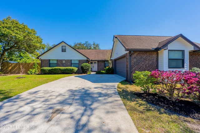 view of front of property with brick siding, an attached garage, a front yard, and fence