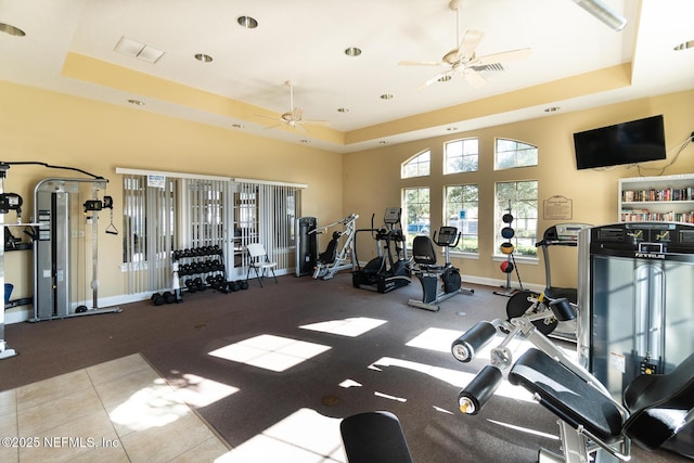 exercise room featuring a raised ceiling, a ceiling fan, baseboards, and visible vents