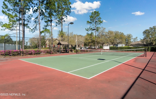 view of tennis court with community basketball court and fence