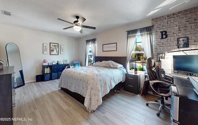 bedroom with wood finish floors, a ceiling fan, visible vents, and a textured ceiling