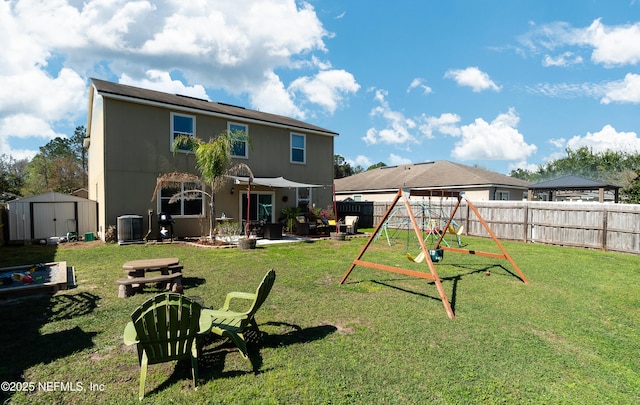 rear view of property with a fenced backyard, an outdoor structure, central air condition unit, a storage shed, and a playground