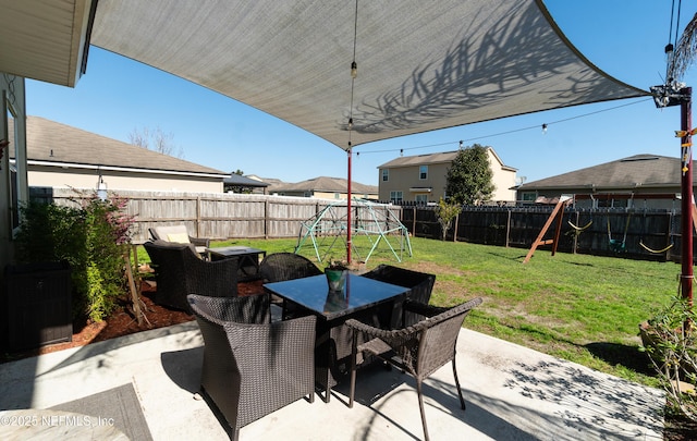 view of patio featuring outdoor dining space, a playground, and a fenced backyard