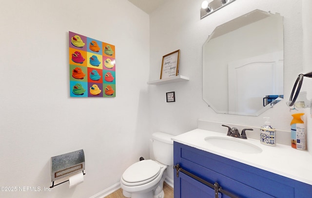 bathroom with baseboards, toilet, wood finished floors, and vanity