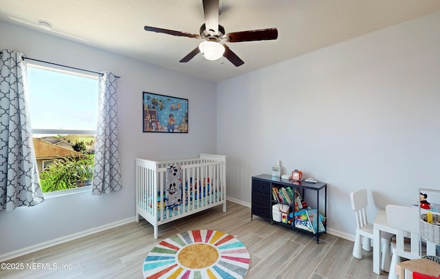 bedroom with wood finish floors, baseboards, and a nursery area