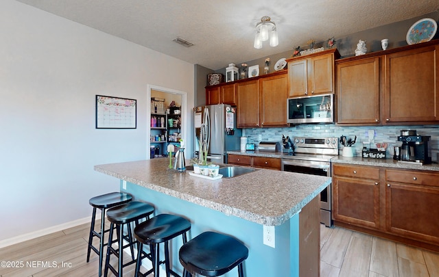 kitchen featuring visible vents, stainless steel appliances, a kitchen breakfast bar, brown cabinets, and a center island