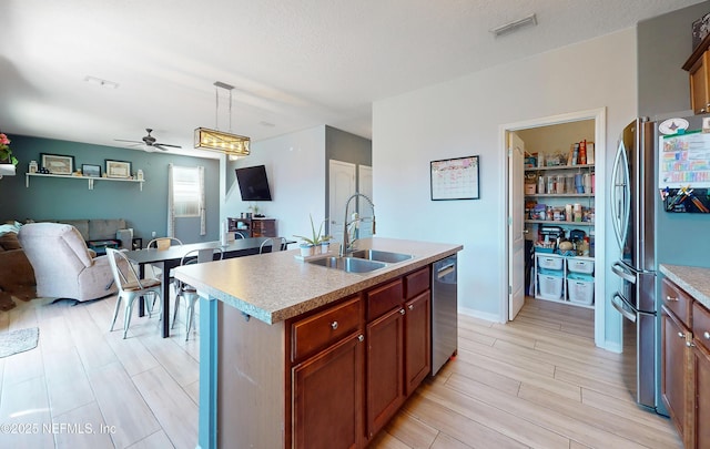 kitchen with visible vents, a sink, open floor plan, stainless steel appliances, and light countertops