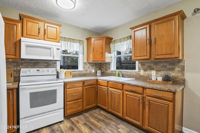 kitchen featuring a sink, white appliances, dark wood-style floors, and brown cabinetry