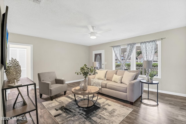 living room with dark wood finished floors, ceiling fan, a textured ceiling, and baseboards