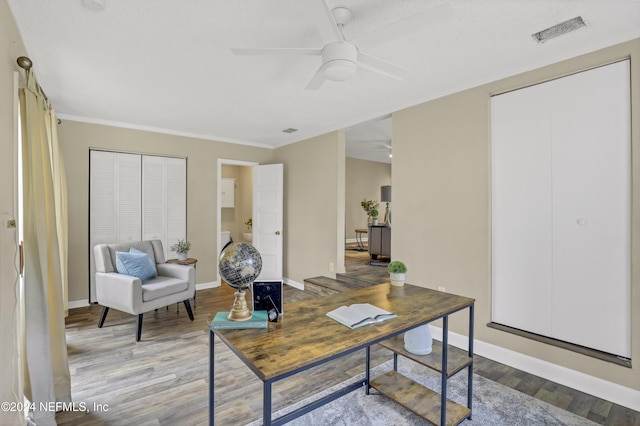 office space featuring a ceiling fan, wood finished floors, visible vents, and baseboards